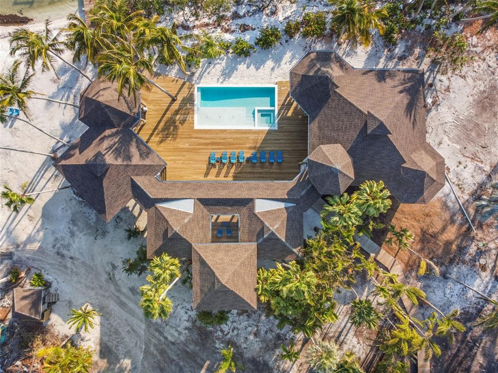 An aerial view shows a house with a shingled roof, wooden deck, and swimming pool — 7147 LA LENAIRE DRIVE, LONGBOAT KEY, FL