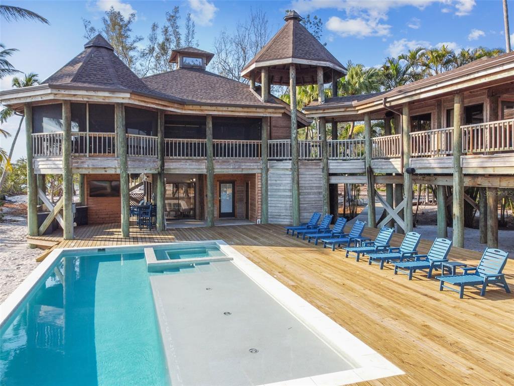 A wooden stilt house with a pool and deck overlooks a sandy beach area — 7147 LA LENAIRE DRIVE, LONGBOAT KEY, FL