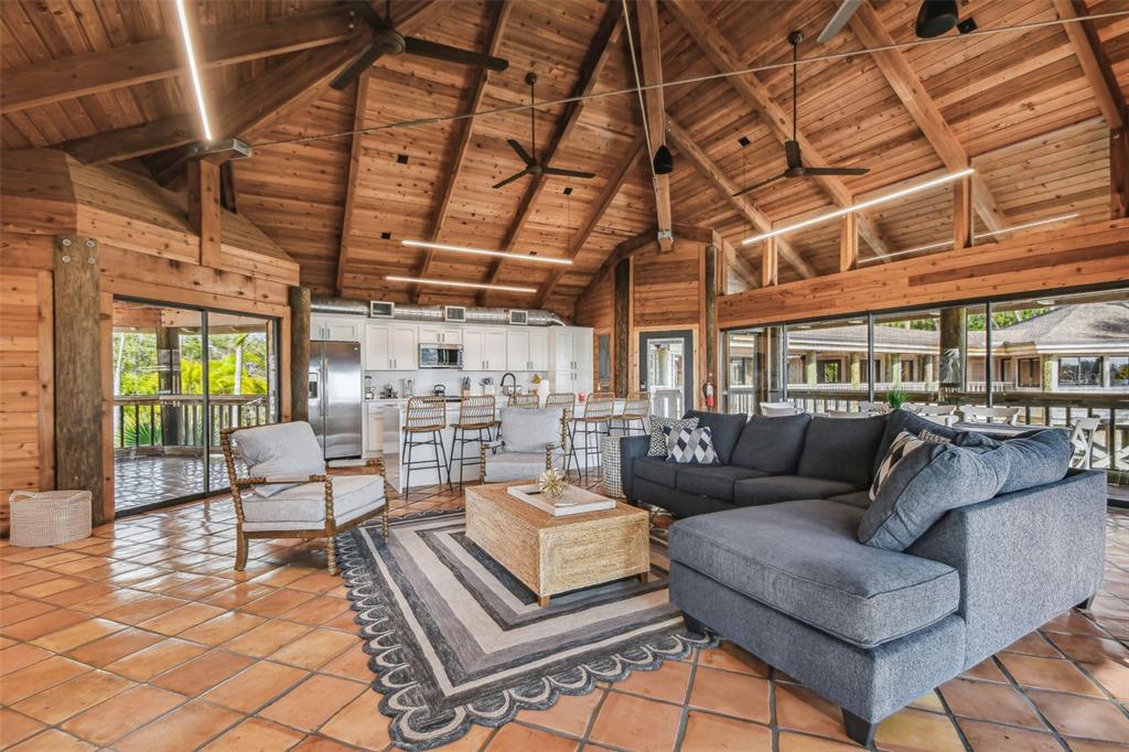 A living room with a vaulted wood ceiling, tile floors, and an open kitchen area — 7147 LA LENAIRE DRIVE, LONGBOAT KEY, FL