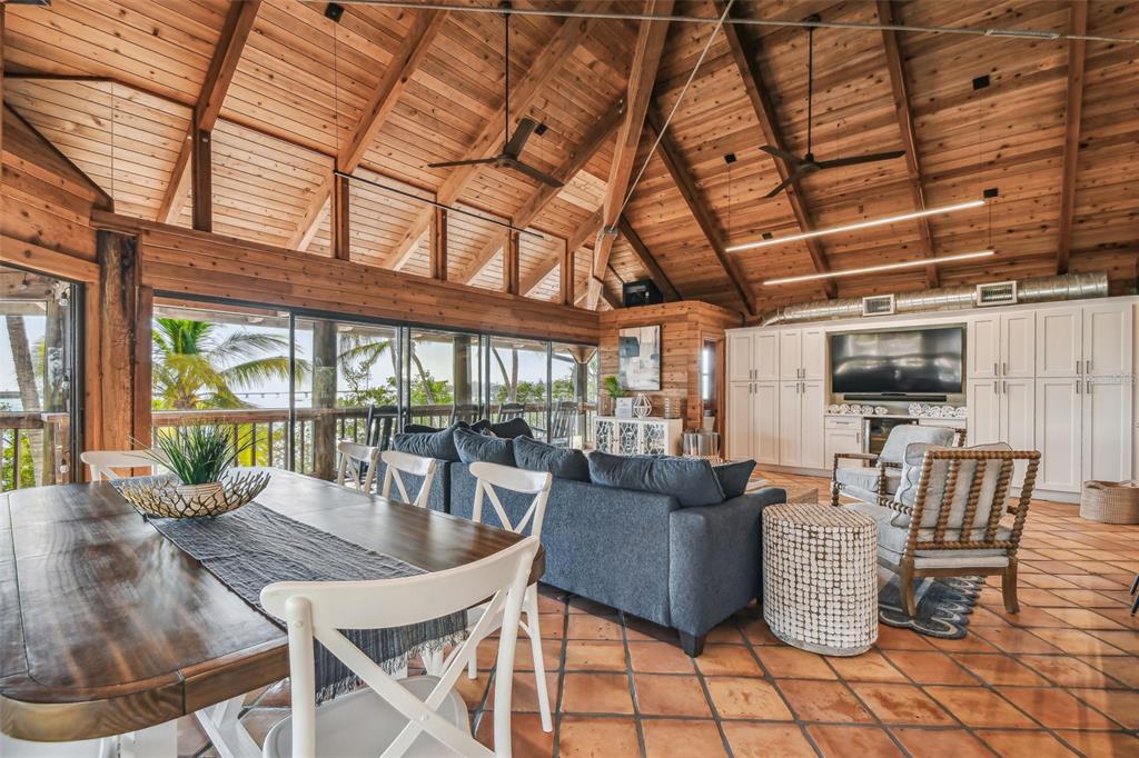 A living and dining area features a vaulted wood ceiling, tile floors, and large windows — 7147 LA LENAIRE DRIVE, LONGBOAT KEY, FL