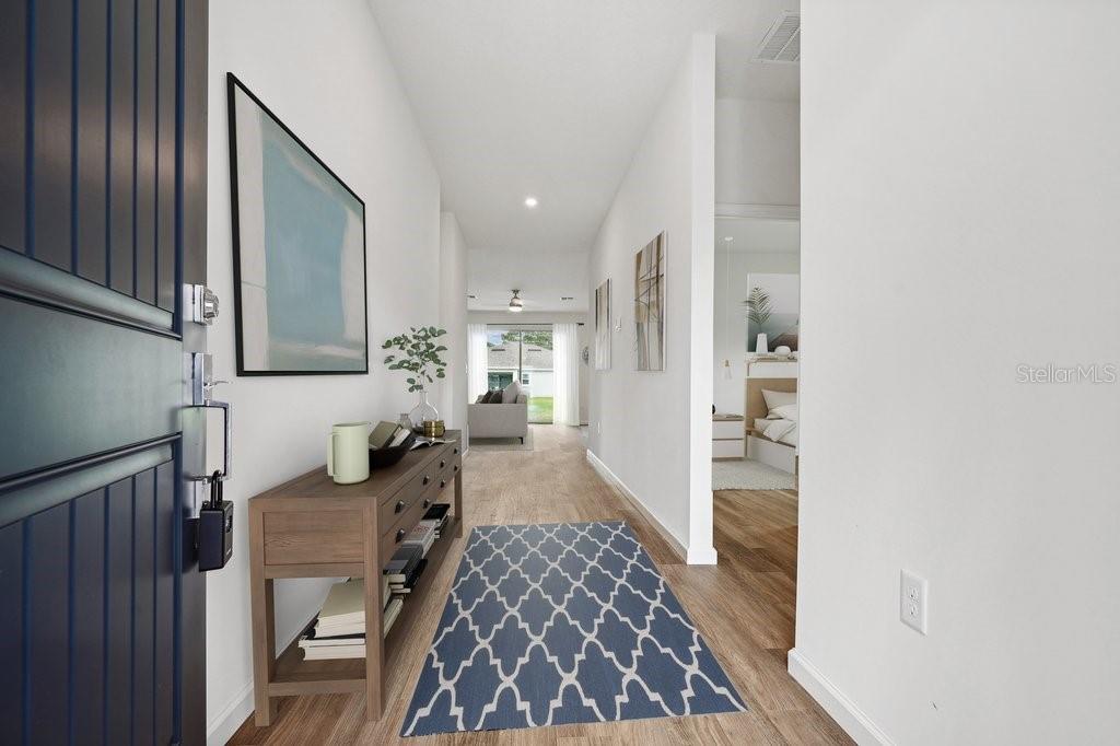 A bright entryway features light wood flooring, a console table, and a blue patterned rug — 23 PORTIA LANE, PALM COAST, FL