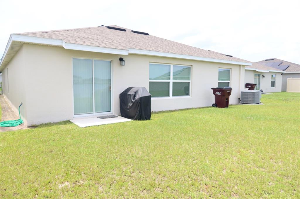 An open-concept living room and kitchen with gray cabinetry, tile flooring, and a sectional sofa — 5121 FOUR STRAND COURT, ST CLOUD, FL