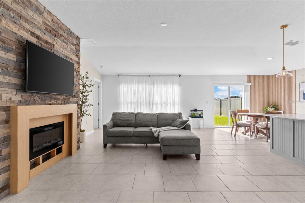A living room with a stone fireplace, gray sectional sofa, and an adjacent dining area — 5121 FOUR STRAND COURT, ST CLOUD, FL