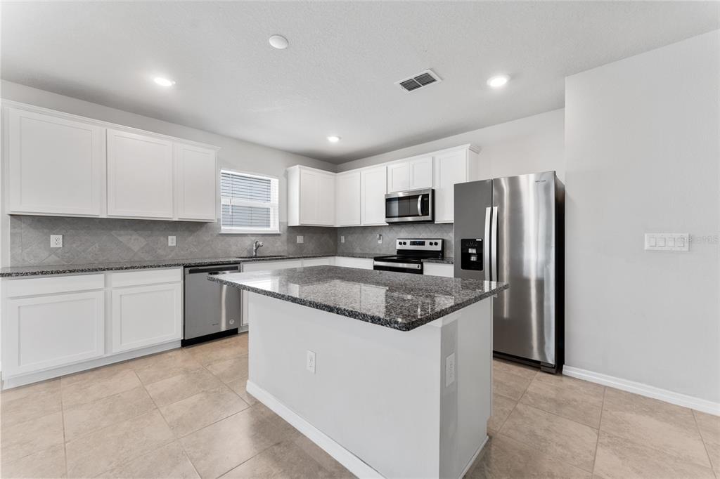 A kitchen with white cabinets, granite countertops, stainless steel appliances, and a central island — 9642 SUMMERS CAY CIRCLE, THONOTOSASSA, FL