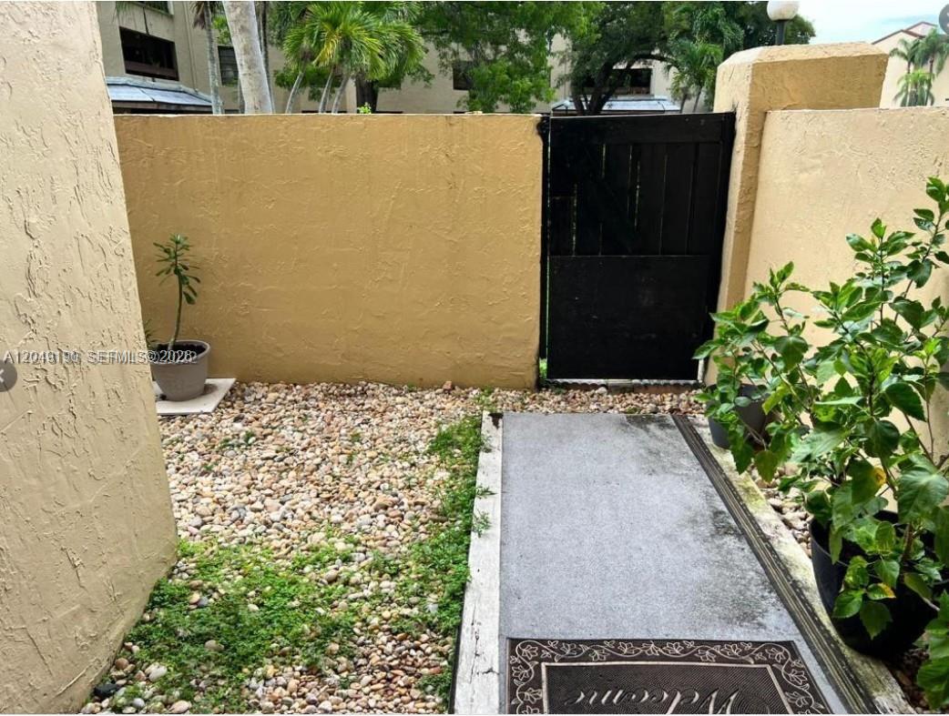 A small outdoor patio features a gravel ground, a concrete walkway, and a black gate — 9255 SW 125th Ave # 106R, Miami FL 33186, MIAMI, FL