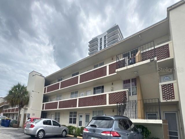 A multi-story apartment building with red accents, exterior staircases, and a parking lot in front — 1770 79TH ST CAUSEWAY UNIT D111, NORTH BAY VILLAGE, FL