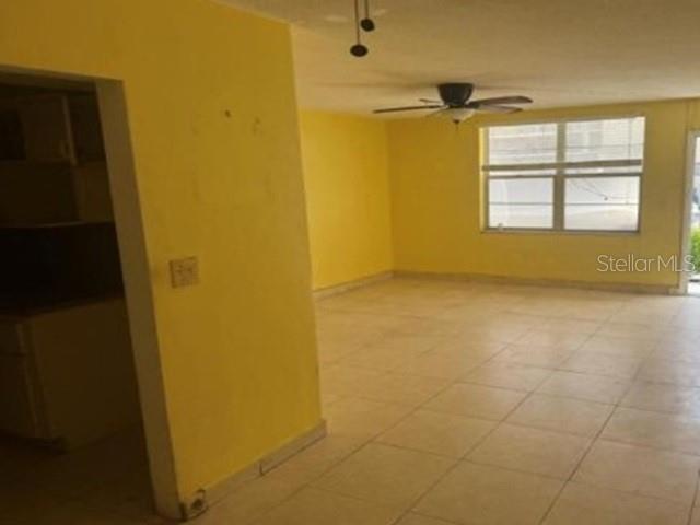 An interior view shows a yellow-walled room with light-colored tile flooring and a ceiling fan — 1770 79TH ST CAUSEWAY UNIT D111, NORTH BAY VILLAGE, FL