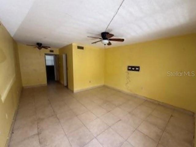 A room with yellow walls, tile flooring, and two ceiling fans — 1770 79TH ST CAUSEWAY UNIT D111, NORTH BAY VILLAGE, FL