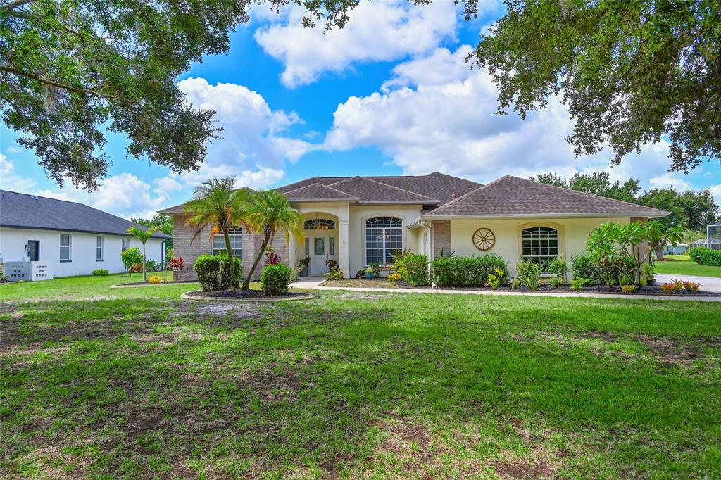 A single-story beige house with a hip roof, arched entryway, and a large front lawn — 14722 1ST AVENUE E, BRADENTON, FL