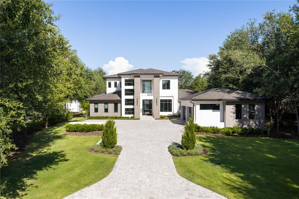 A modern two-story house with a paved driveway, white stucco walls, and dark gray trim — 15746 PENDIO DR, MONTVERDE, FL