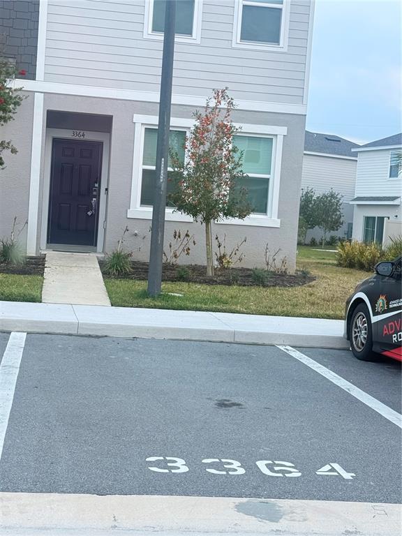 A two-story residential building features a dark front door and a designated parking space — 3364 COMPOSITION STREET UNIT 3364, KISSIMMEE, FL