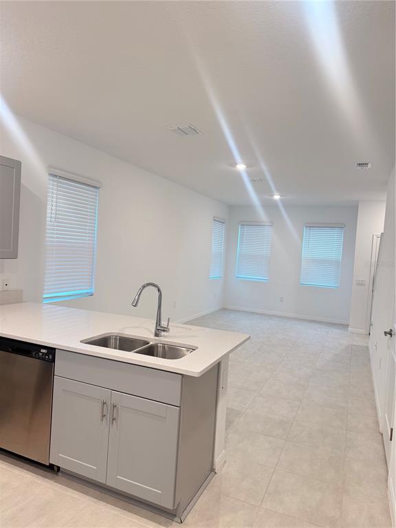 A kitchen island with a sink overlooks an open-concept living area with tiled floors — 3364 COMPOSITION STREET UNIT 3364, KISSIMMEE, FL