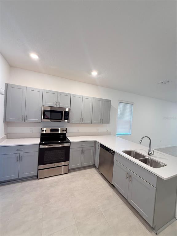 A kitchen features light gray cabinets, white countertops, stainless steel appliances, and tile flooring — 3364 COMPOSITION STREET UNIT 3364, KISSIMMEE, FL