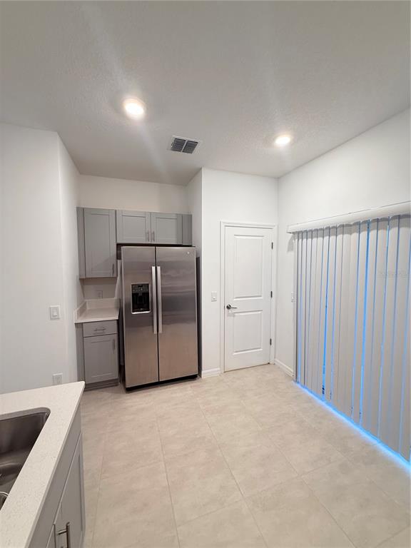 A kitchen features gray cabinets, stainless steel appliances, and tile flooring near a sliding glass door — 3364 COMPOSITION STREET UNIT 3364, KISSIMMEE, FL