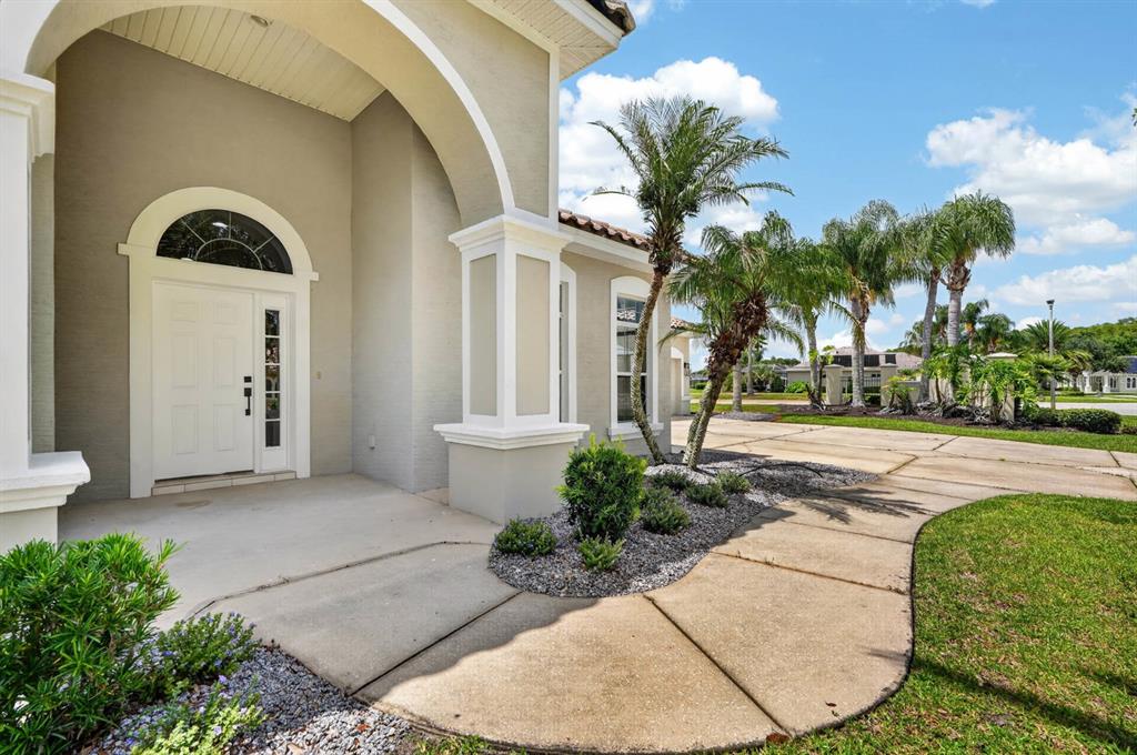 A beige house exterior features a white arched front door and a curved concrete walkway — 3555 MARIBELLA DRIVE, NEW SMYRNA BEACH, FL