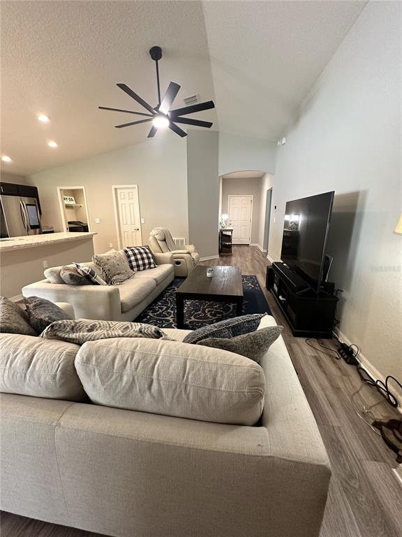A living room features a vaulted ceiling, a large sectional sofa, and a television console — 6911 GIDEON CIR, ZEPHYRHILLS, FL