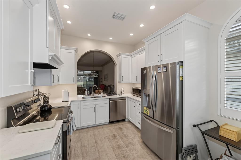 A kitchen features white cabinets, stainless steel appliances, quartz countertops, and light-colored tile flooring — 5633 E LONG COMMON COURT UNIT 20, SARASOTA, FL