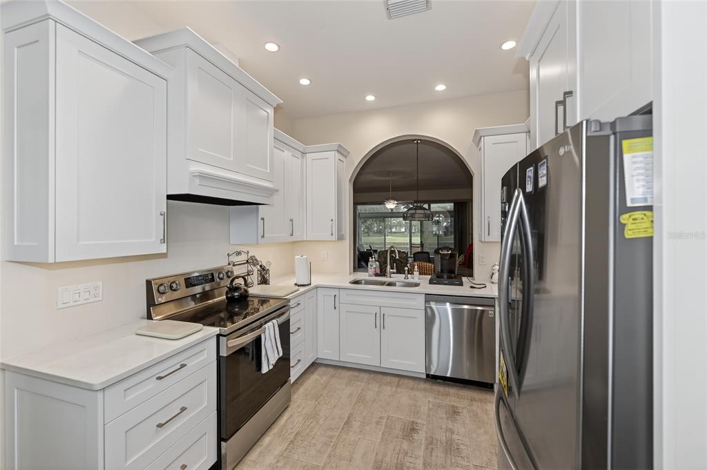 A kitchen with white cabinets, stainless steel appliances, and a view through an arched window — 5633 E LONG COMMON COURT UNIT 20, SARASOTA, FL