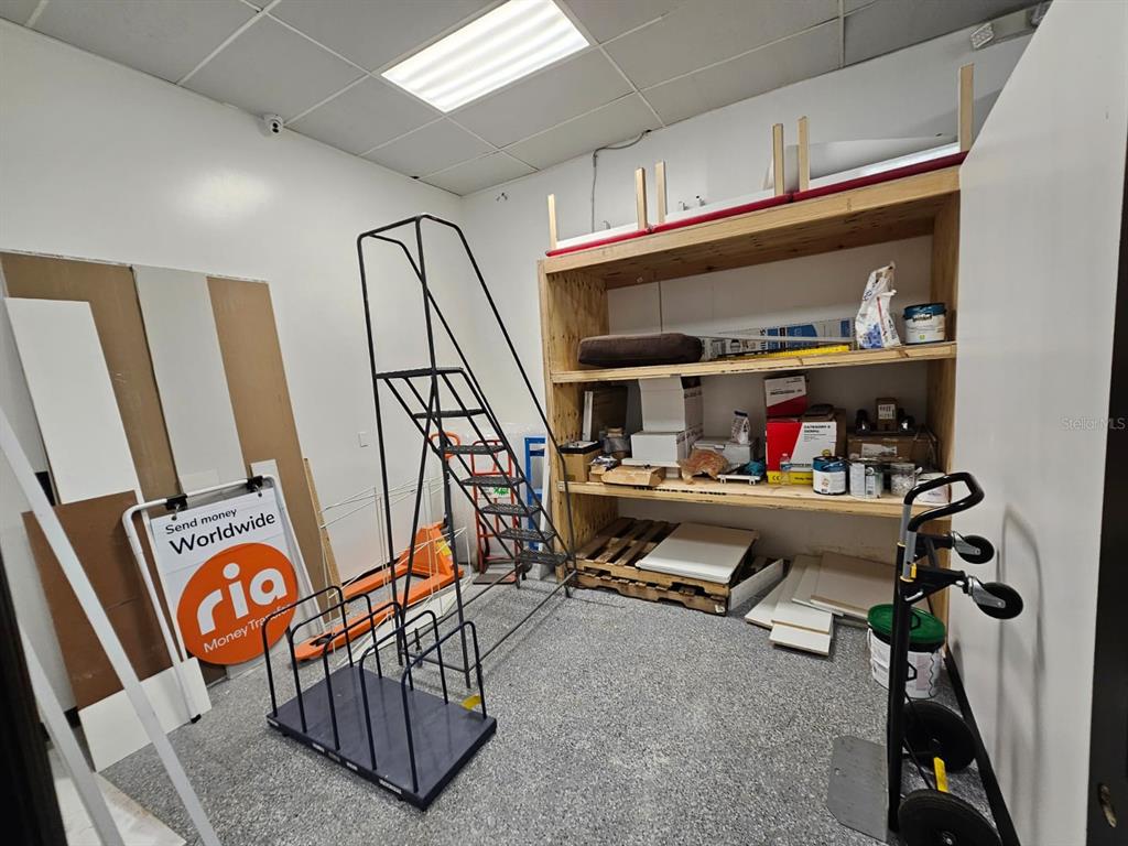 A storage room features a metal rolling ladder, wooden shelving units, and a Ria sign — 624 S PINE AVENUE, OCALA, FL