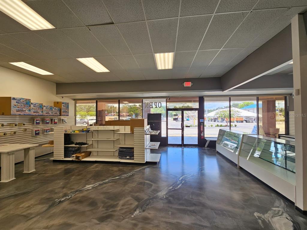 An empty retail space features a polished gray floor, white shelving units, and glass display cases — 624 S PINE AVENUE, OCALA, FL