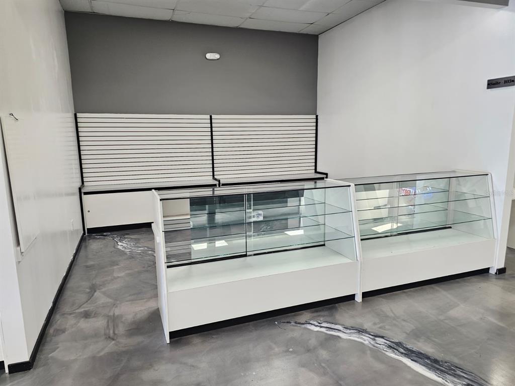 An empty retail space features glass display cases, white slat walls, and a marbled floor — 624 S PINE AVENUE, OCALA, FL