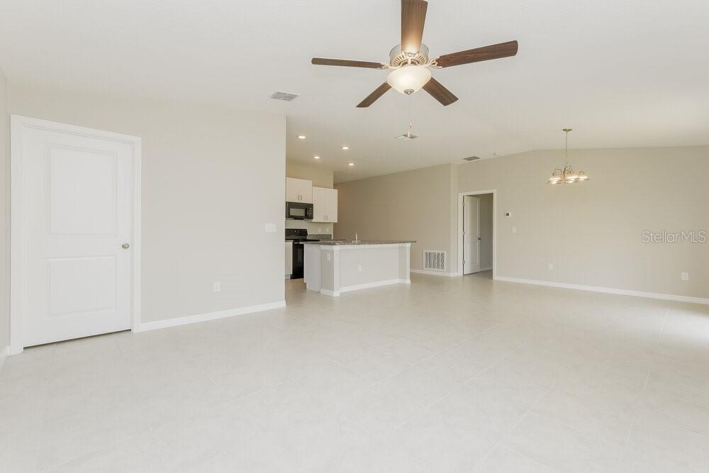 An open-concept living area features light tile flooring, a ceiling fan, and a kitchen island — 11515 SAGE CANYON DRIVE, RIVERVIEW, FL