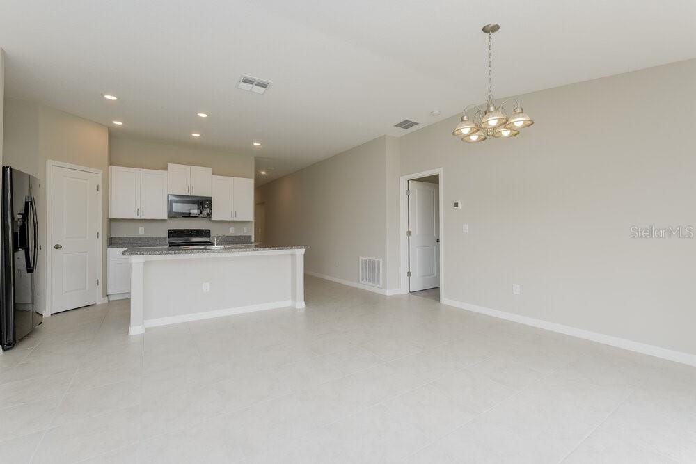 A kitchen with white cabinets and a breakfast bar opens into a spacious living area — 11515 SAGE CANYON DRIVE, RIVERVIEW, FL