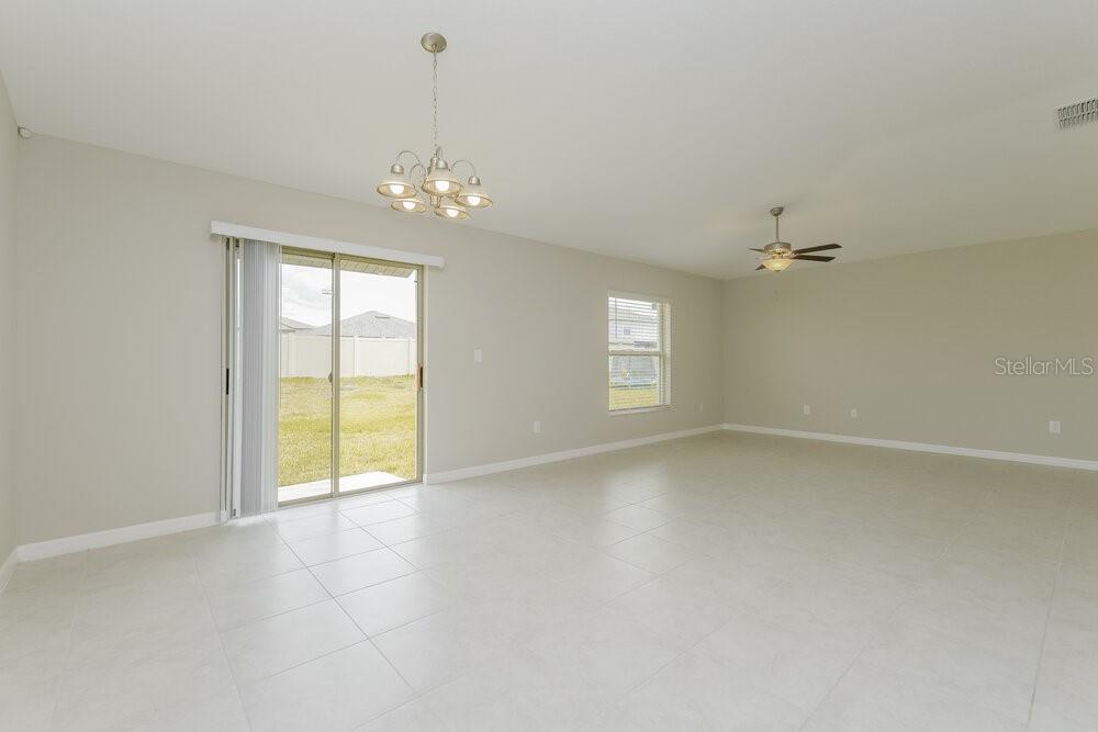 A spacious room with light tile flooring, a chandelier, a ceiling fan, and sliding doors — 11515 SAGE CANYON DRIVE, RIVERVIEW, FL