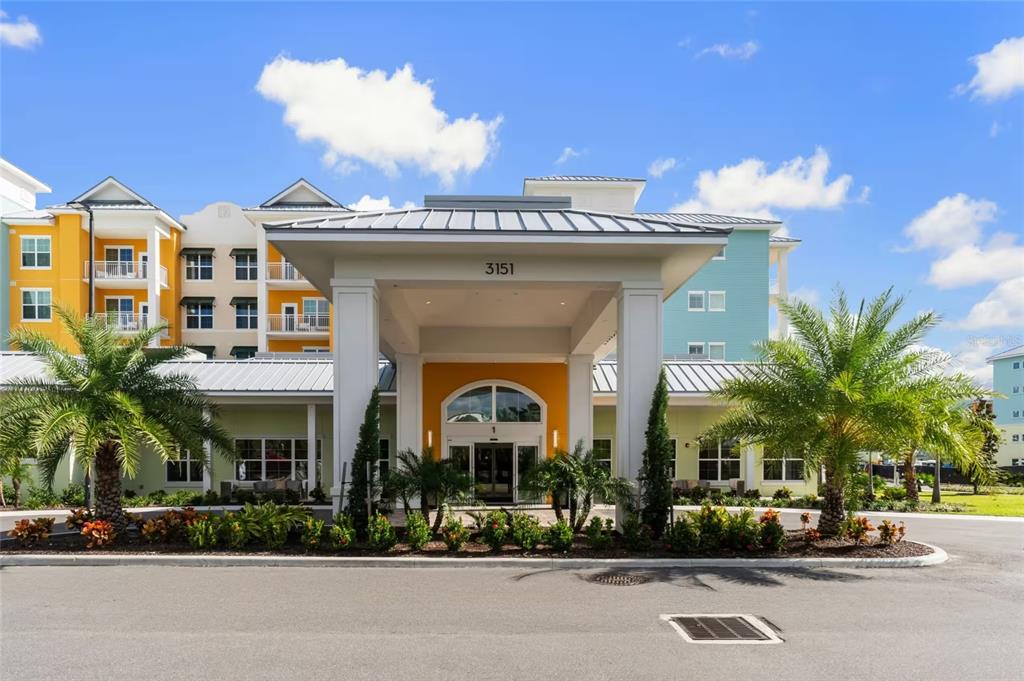 A multi-story building with a covered entrance, palm trees, and colorful exterior walls — 3151 SUNSET WALK DRIVE UNIT 1316 and 1318, KISSIMMEE, FL