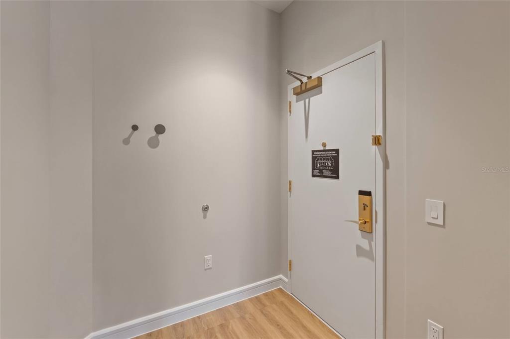 An interior view shows a white door with a door closer and light-colored wood flooring — 3151 SUNSET WALK DRIVE UNIT 1316 and 1318, KISSIMMEE, FL