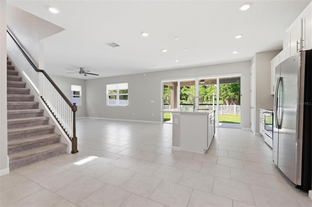 A modern kitchen with white cabinets, stainless steel appliances, and a view of the backyard — 1037 RIVER OTTER WAY, DELAND, FL