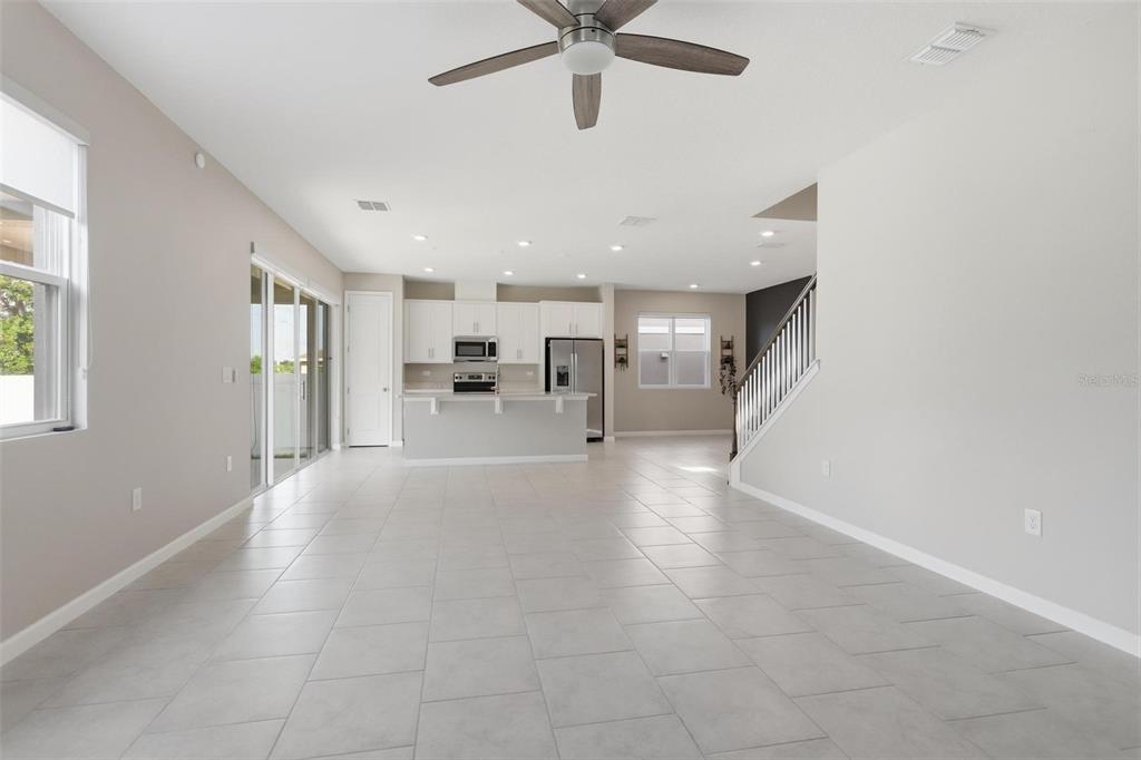 A modern kitchen features white cabinets, stainless steel appliances, a quartz island, and tile flooring — 1037 RIVER OTTER WAY, DELAND, FL