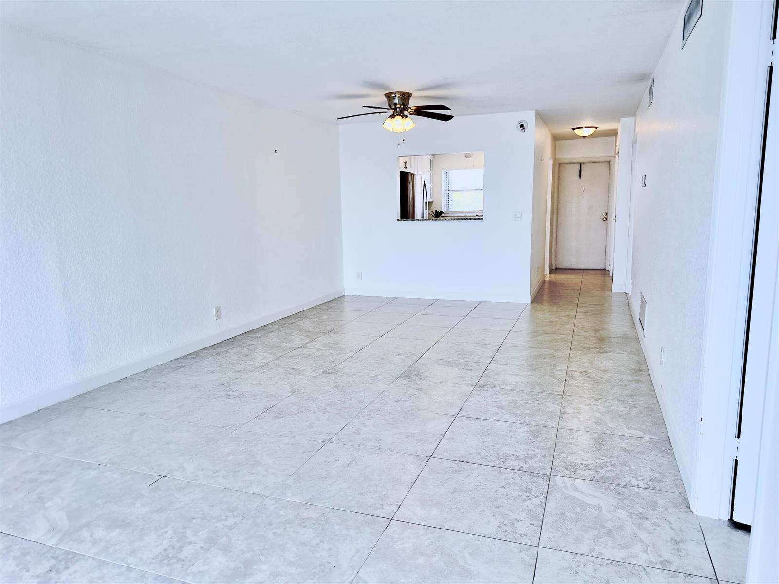 An empty living room features white walls, light-colored tile flooring, and a ceiling fan — 2016 S Federal Highway # 404, Boynton Beach FL 33435, BOYNTON BEACH, FL