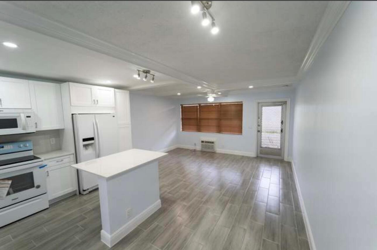 A kitchen with white cabinets and a small island opens into a living area — 309 Windsor N, West Palm Beach FL 33417, WEST PALM BEACH, FL