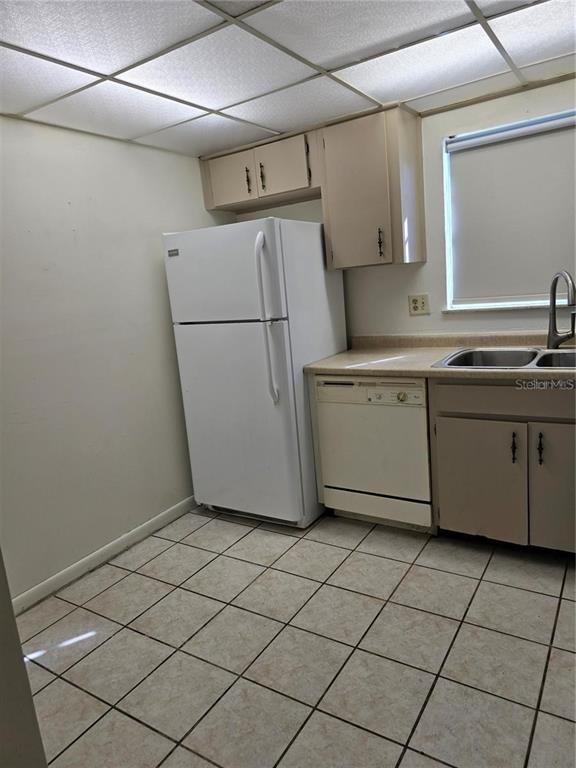 A kitchen features white appliances, beige cabinets, a double sink, and light-colored tile flooring — 712 OAKGROVE DRIVE UNIT 230, BRANDON, FL