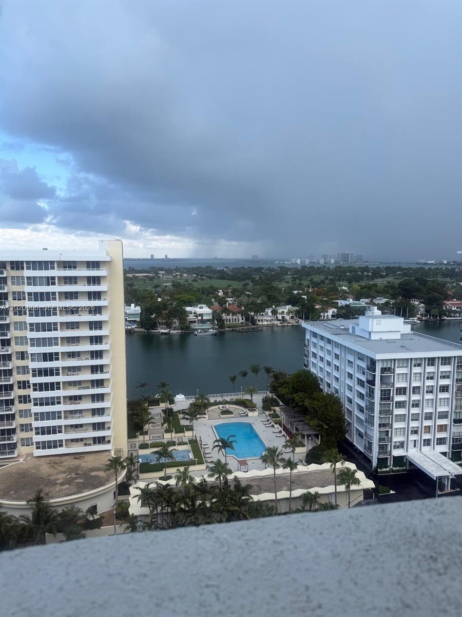 An elevated view shows two apartment buildings flanking a swimming pool and a waterway — 5601 Collins Ave # 1718, Miami Beach FL 33140, MIAMI BEACH, FL