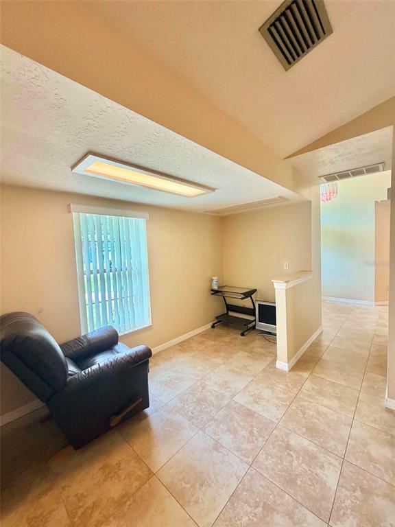A room with tile flooring, a recliner, and a small desk against a half wall — 5647 DALTON COURT, NEW PORT RICHEY, FL