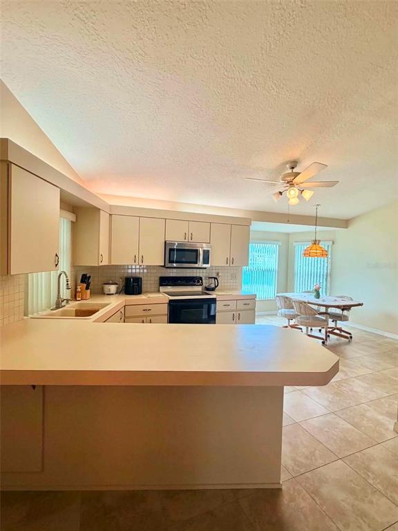 A kitchen with light-colored cabinets and a breakfast bar overlooks a dining area — 5647 DALTON COURT, NEW PORT RICHEY, FL