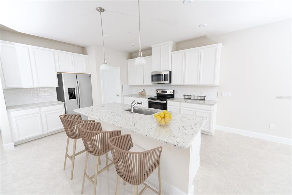 A modern kitchen features white cabinets, granite countertops, a central island, and three bar stools — 6704 CEDAR LANDING CIRCLE, LEESBURG, FL