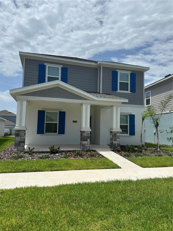 A two-story house with a covered front porch, blue shutters, and stone-accented columns — 2981 GOOD VIBES WAY, CLERMONT, FL