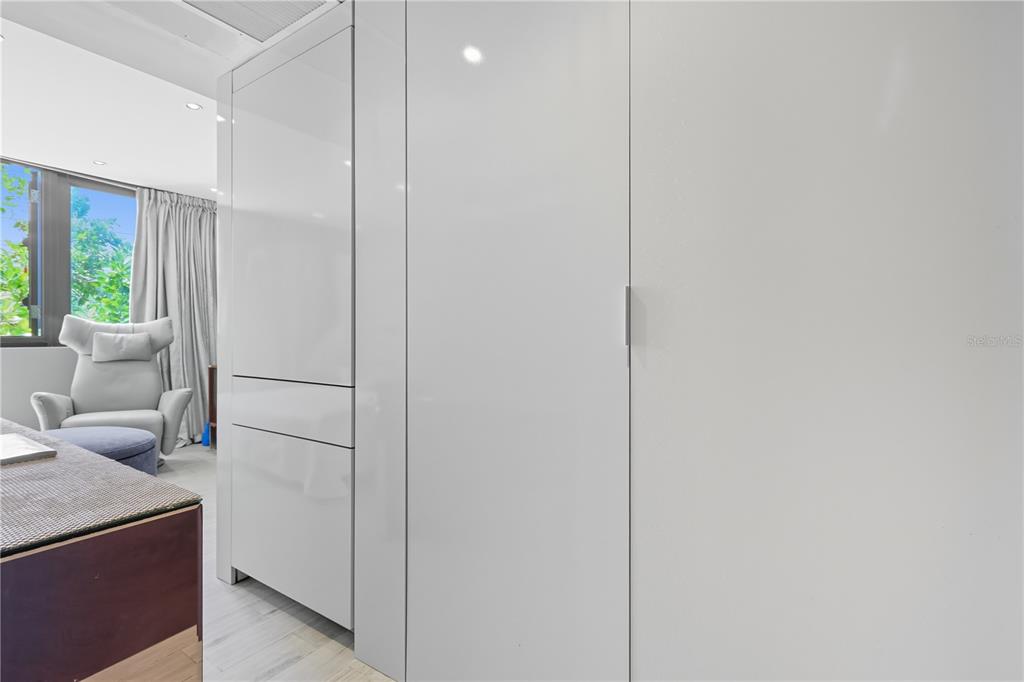 A room features white high-gloss cabinetry, a modern armchair, and a window with curtains — 63 KINGS CT UNIT #3A, SAN JUAN, PR