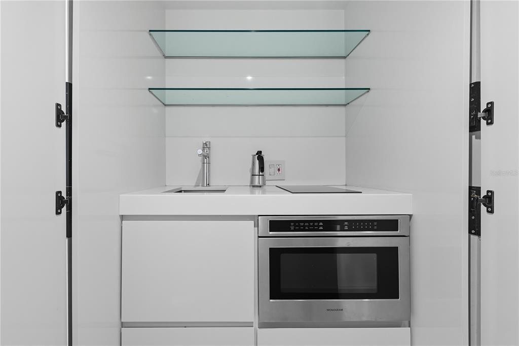 A modern kitchenette features white cabinetry, glass shelves, a sink, and a built-in microwave — 63 KINGS CT UNIT #3A, SAN JUAN, PR