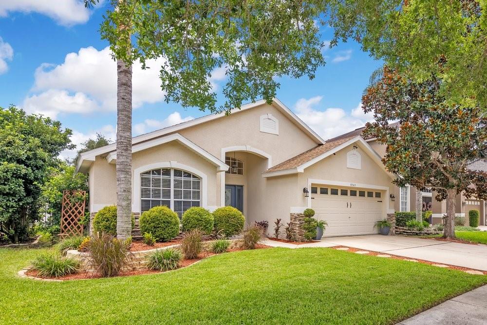 A single-story house with a beige stucco exterior, a two-car garage, and a landscaped lawn — 9745 DORIATH CIRCLE, ORLANDO, FL