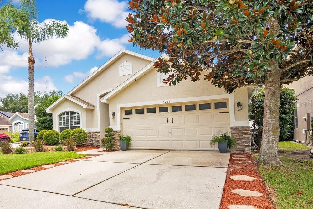 A single-story house with a beige stucco exterior, stone accents, and a two-car garage — 9745 DORIATH CIRCLE, ORLANDO, FL