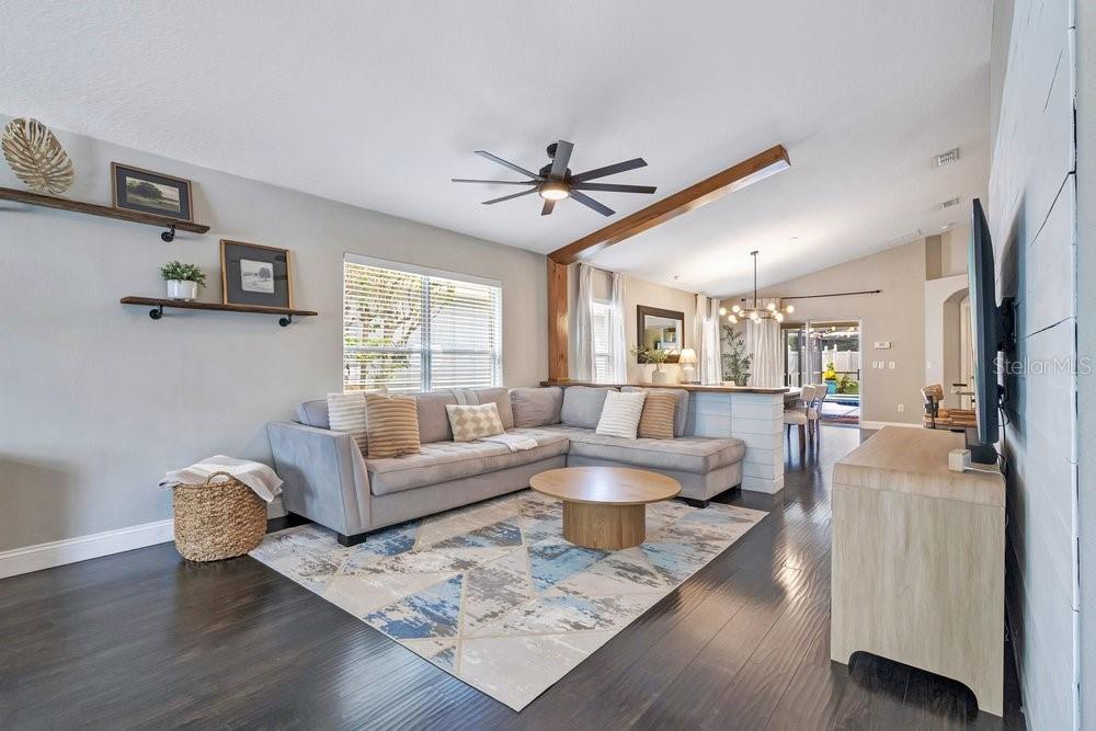 A living room features a gray sectional sofa, a round wooden coffee table, and dark flooring — 9745 DORIATH CIRCLE, ORLANDO, FL