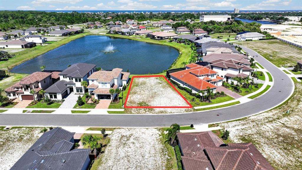 An aerial view shows a vacant residential lot outlined in red next to a lake — 47 DEL PALMA DRIVE, PALM COAST, FL
