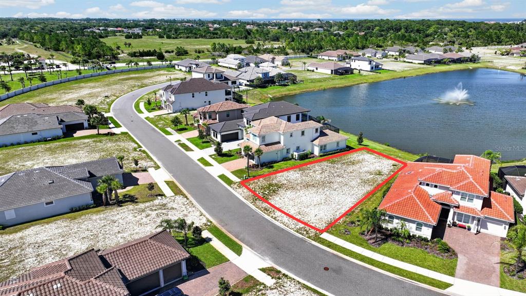 An aerial view shows a vacant residential lot outlined in red next to a lake — 47 DEL PALMA DRIVE, PALM COAST, FL