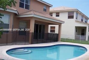 A backyard swimming pool with a safety fence sits behind a two-story tan house — 13161 SW 45th Dr, Miramar FL 33027, MIRAMAR, FL