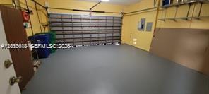 An empty garage with a gray epoxy floor, yellow walls, and a metal sectional door — 13161 SW 45th Dr, Miramar FL 33027, MIRAMAR, FL