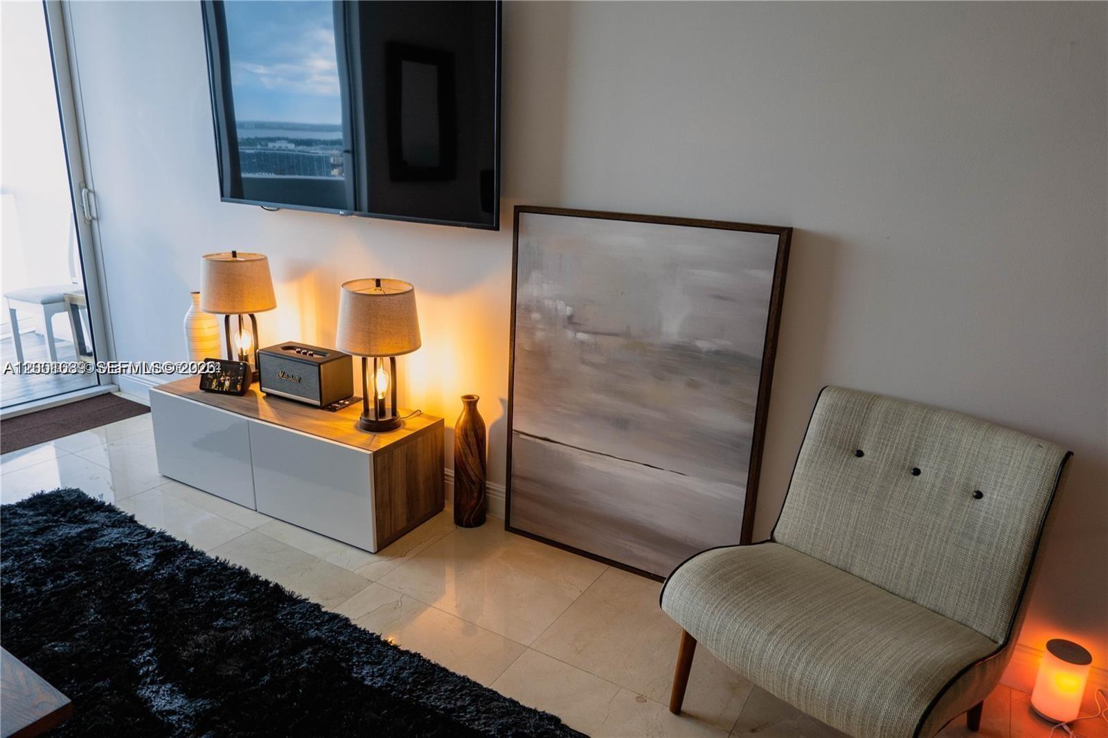 A modern living room features a television, media console, abstract art, and an accent chair — 6365 Collins Ave # 2710, Miami Beach FL 33141, MIAMI BEACH, FL